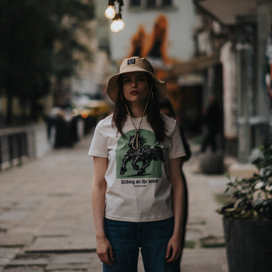Person wearing a white t-shirt with a graphic design on a city street.